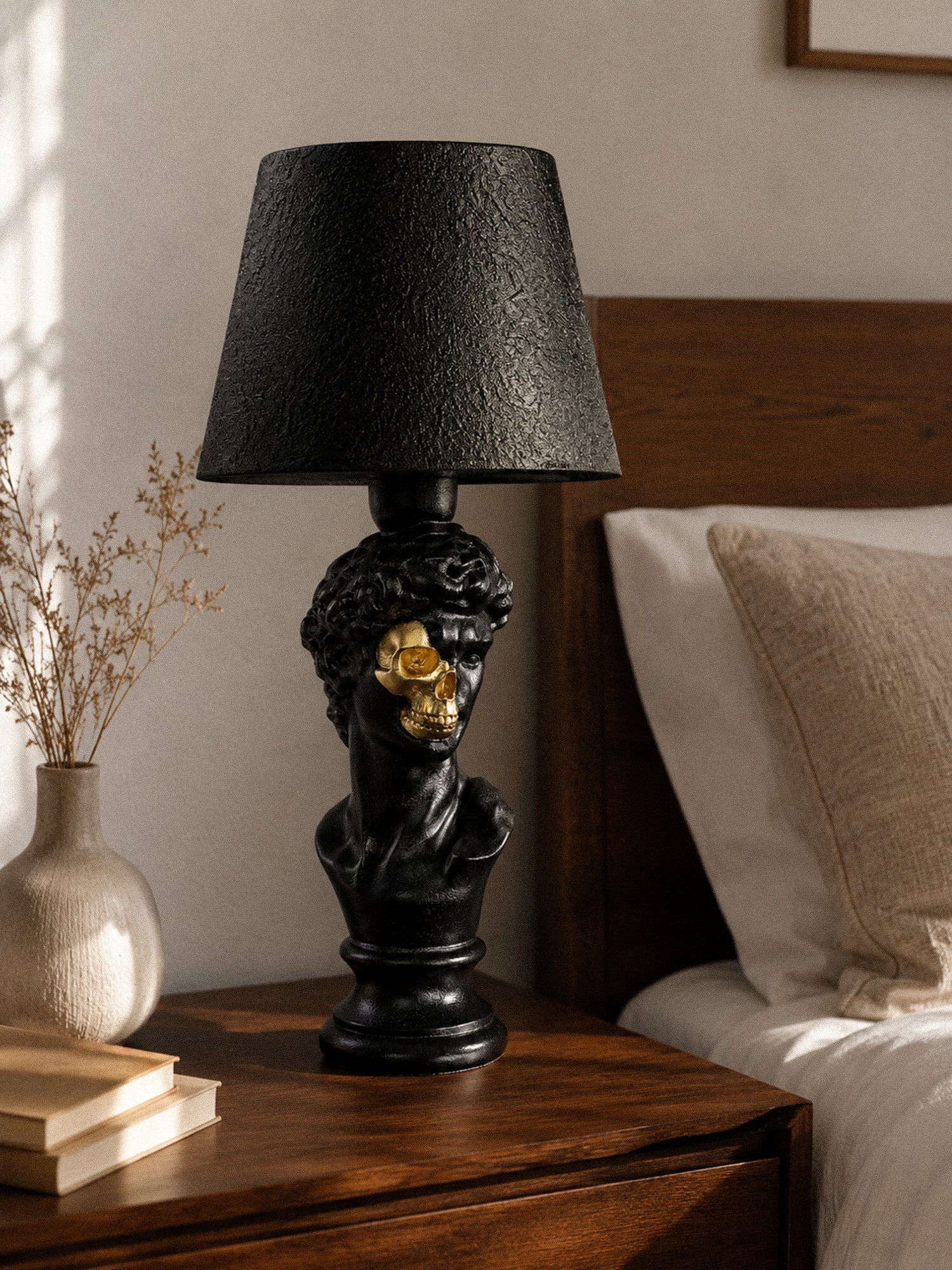 David half-skull sculptural lamp on an wooden bedside table in a warm bedroom
