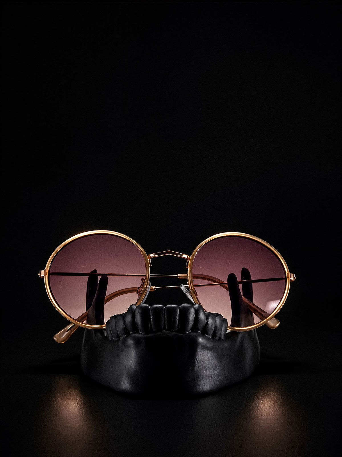 Front view of Bite, a black sculptural jawbone holder supporting round sunglasses.