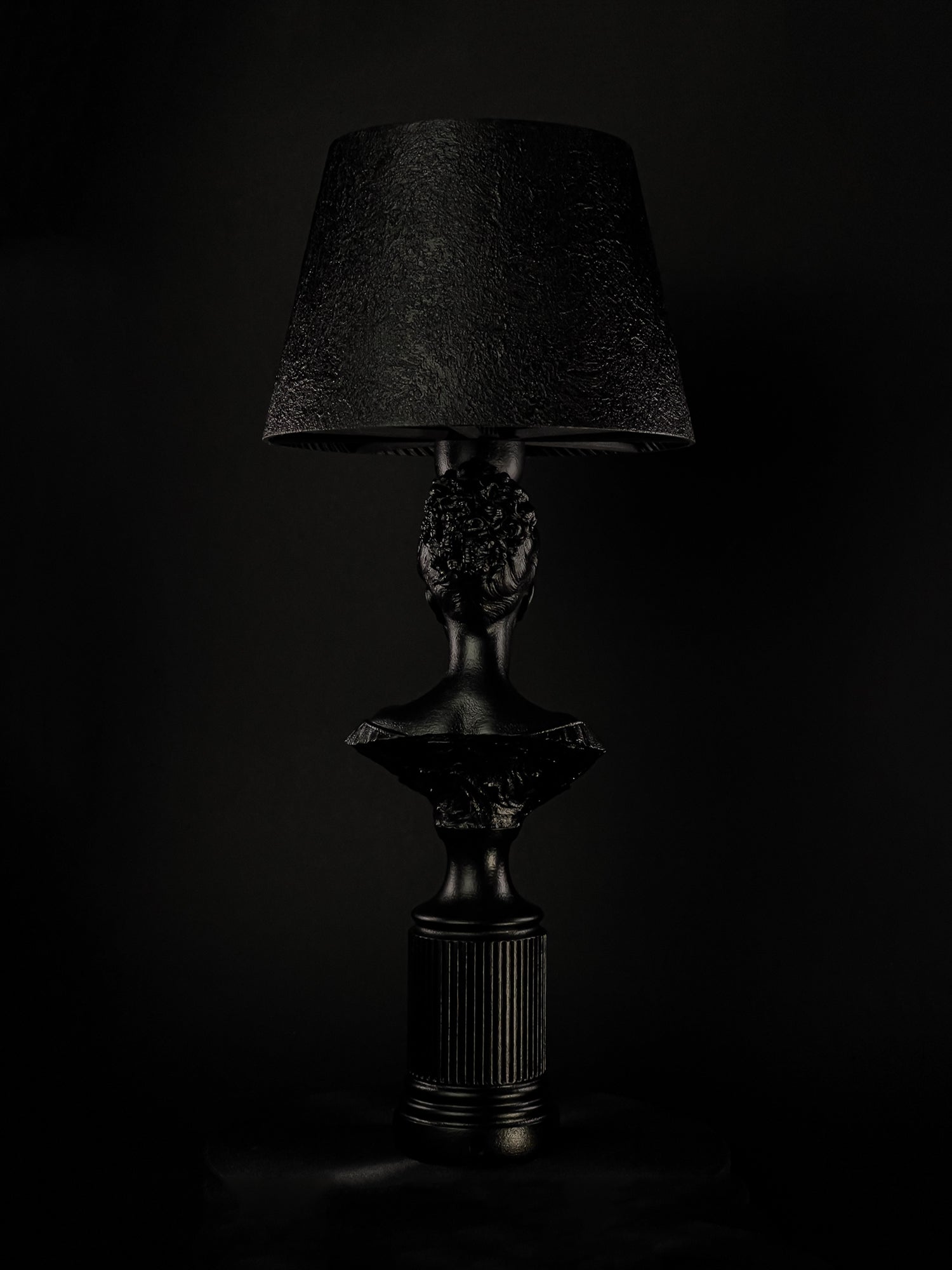 Back view of the satin-black Blind Hera bust lamp and fluted pedestal