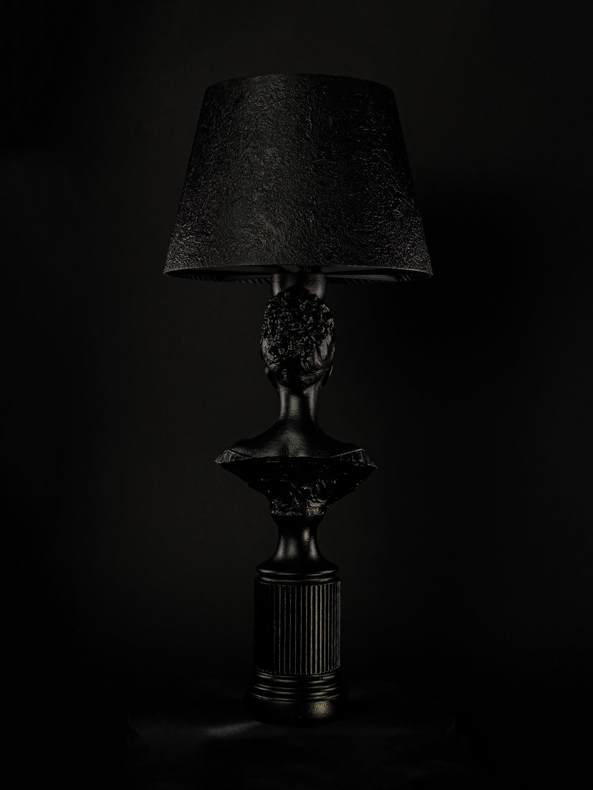 Back view of the satin-black Blind Hera bust lamp and fluted pedestal