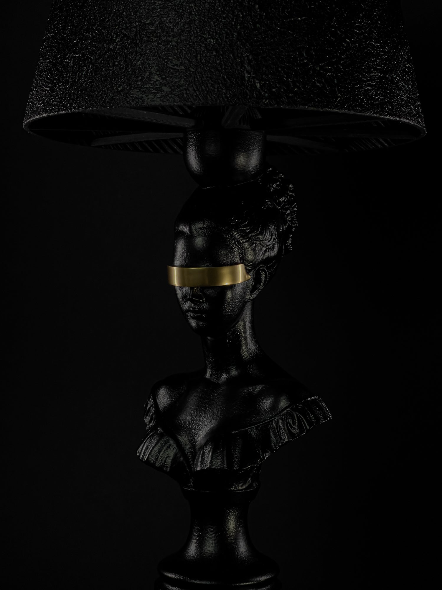 Close-up of the Blind Hera sculptural lamp with gold blindfold beneath its textured shade