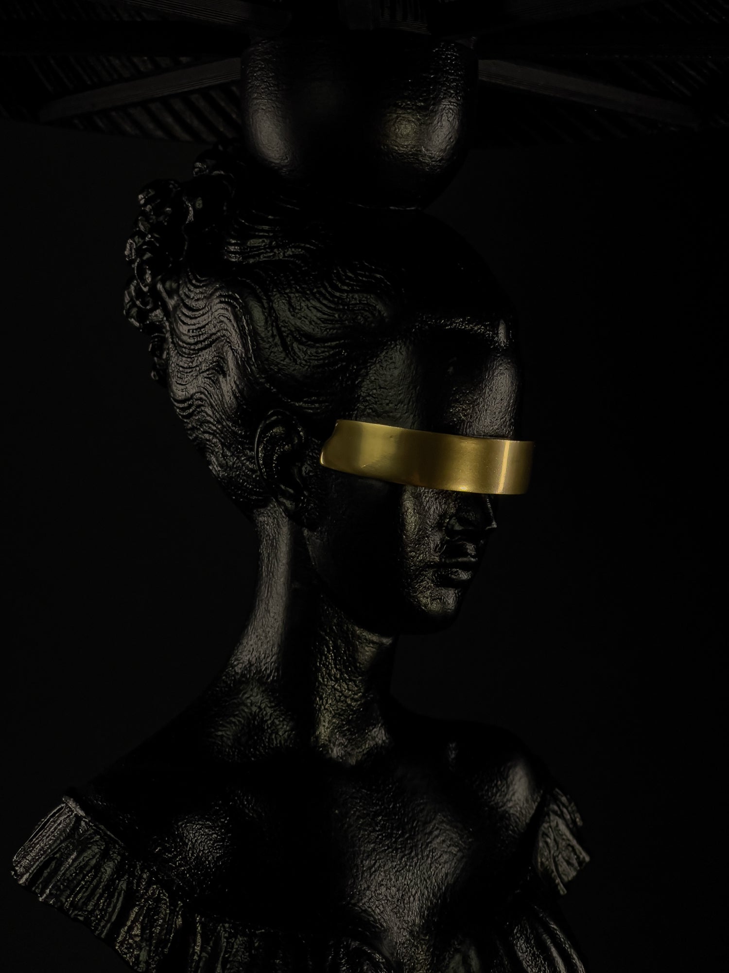 Detail view of Blind Hera’s gold blindfold and hand-finished black classical bust