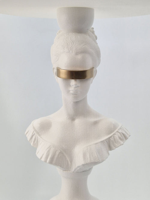 Close-up of the Blind Hera lamp's gold-plated blindfold and intricate white sculpture facial features.