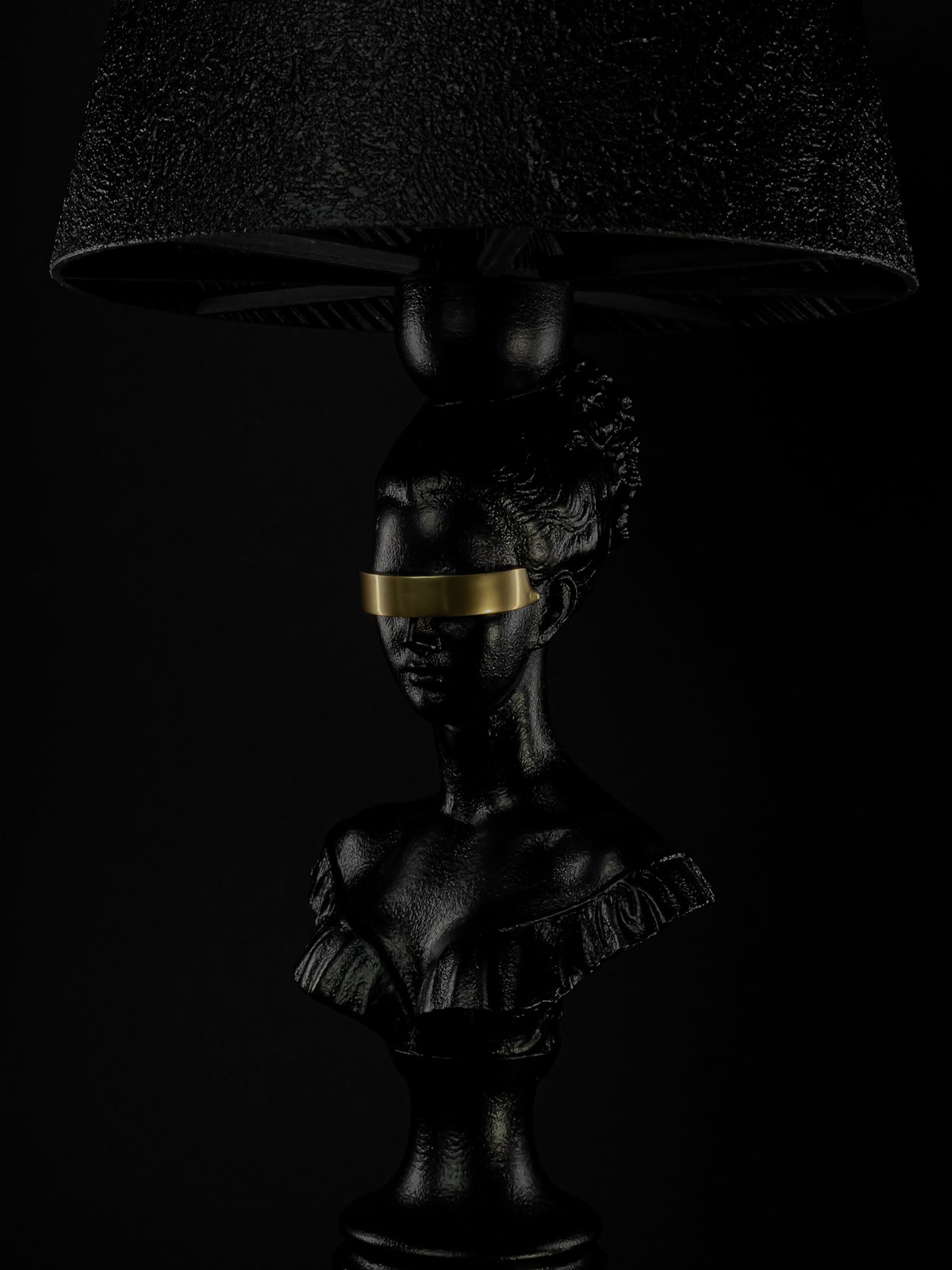 Close-up of the Blind Hera sculptural lamp with gold blindfold beneath its textured shade