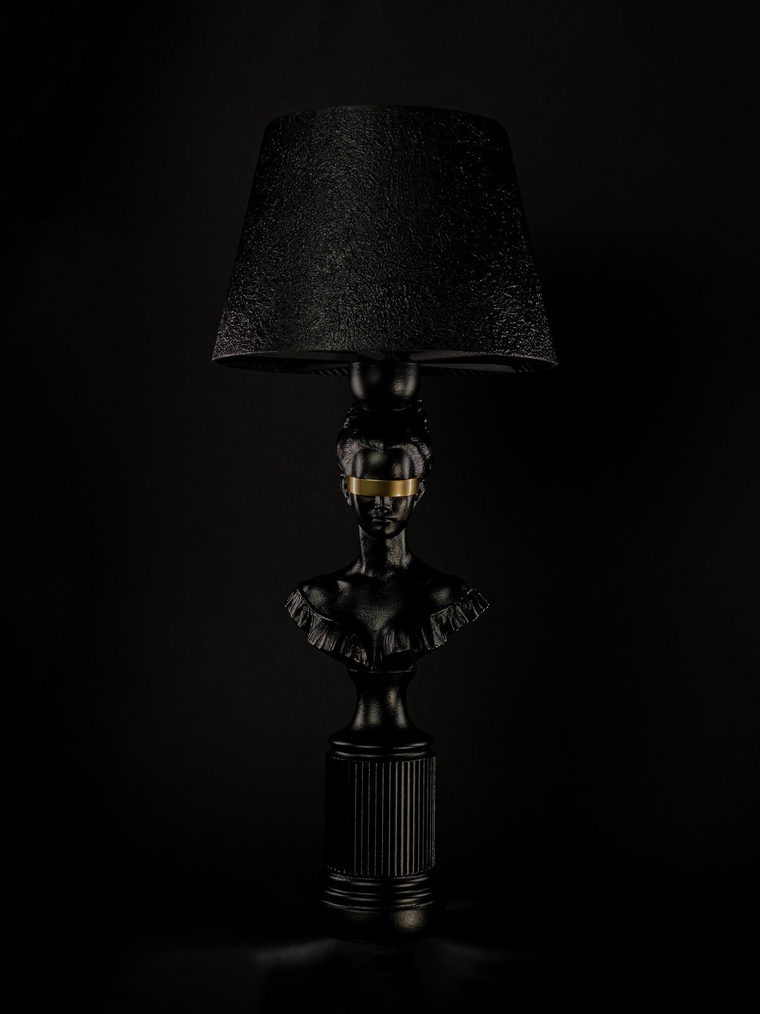 Blind Hera sculptural lamp in satin black with a metallic-gold blindfold, shown from a three-quarter angle