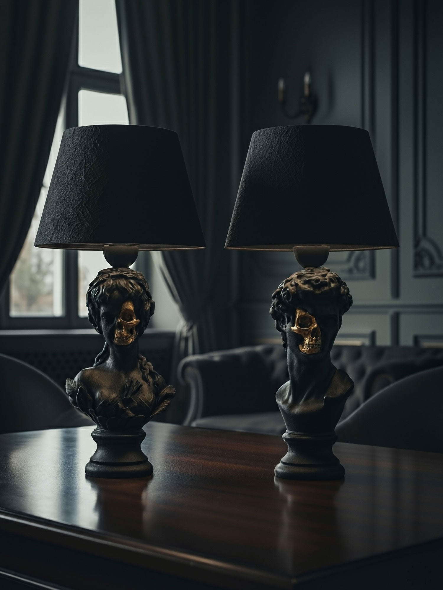 Lifestyle shot of the Venus and David half-skull lamps on a mahogany table in a moody gothic room by Horror Romance.
