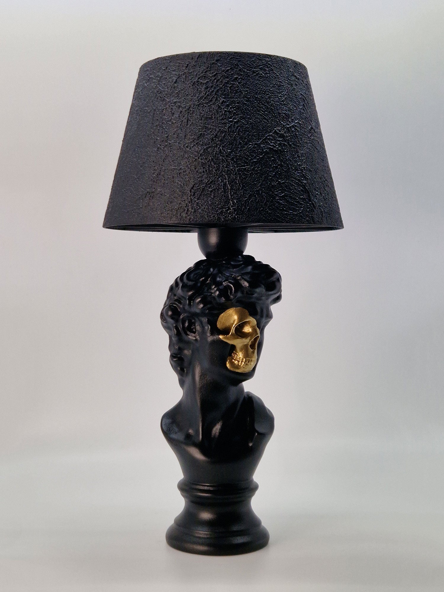 Angled view of the David bust lamp showing the intricate hair texture and gold-plated skull face.