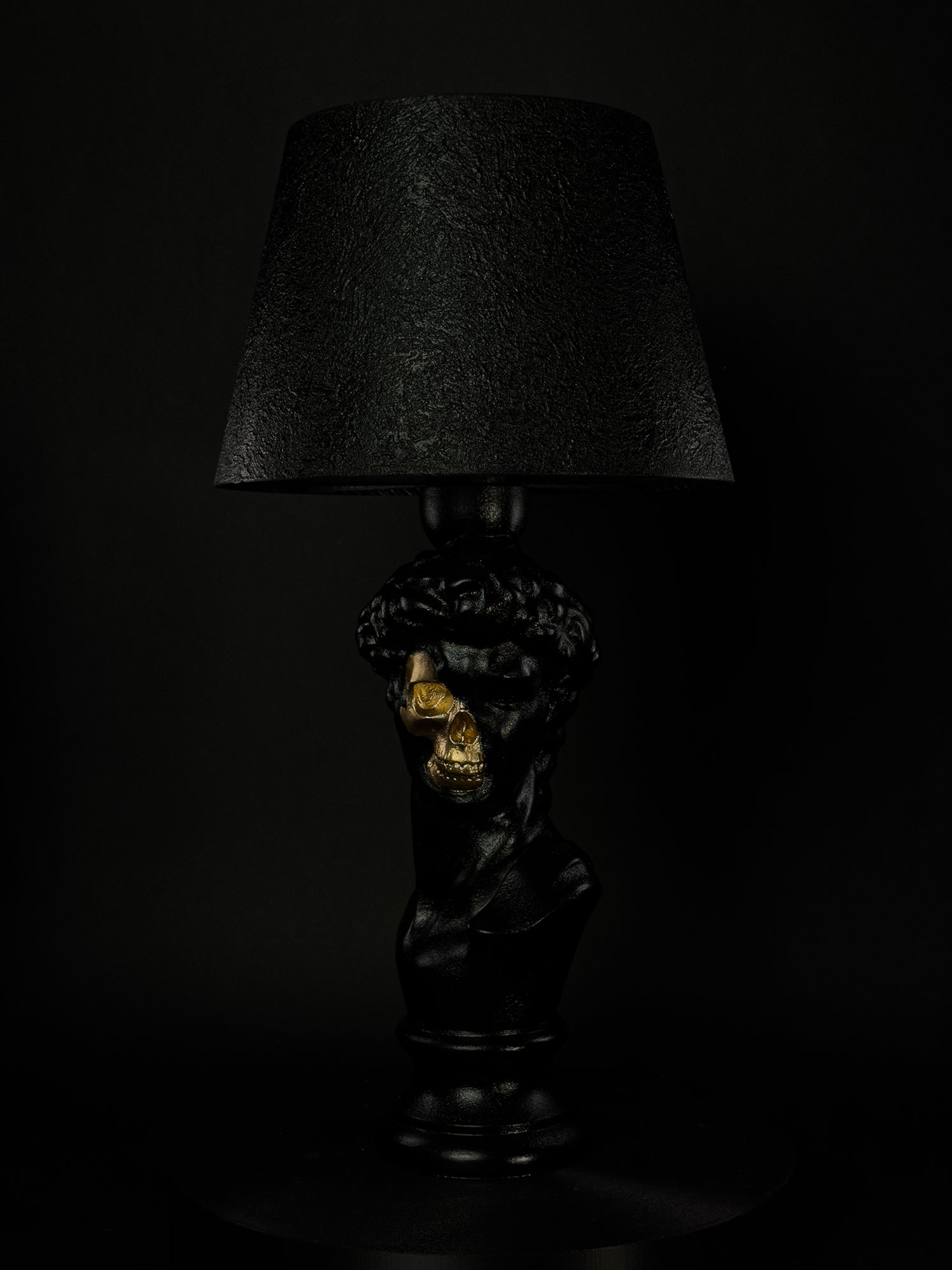 Front view of the black David classical bust lamp with exposed metallic-gold skull