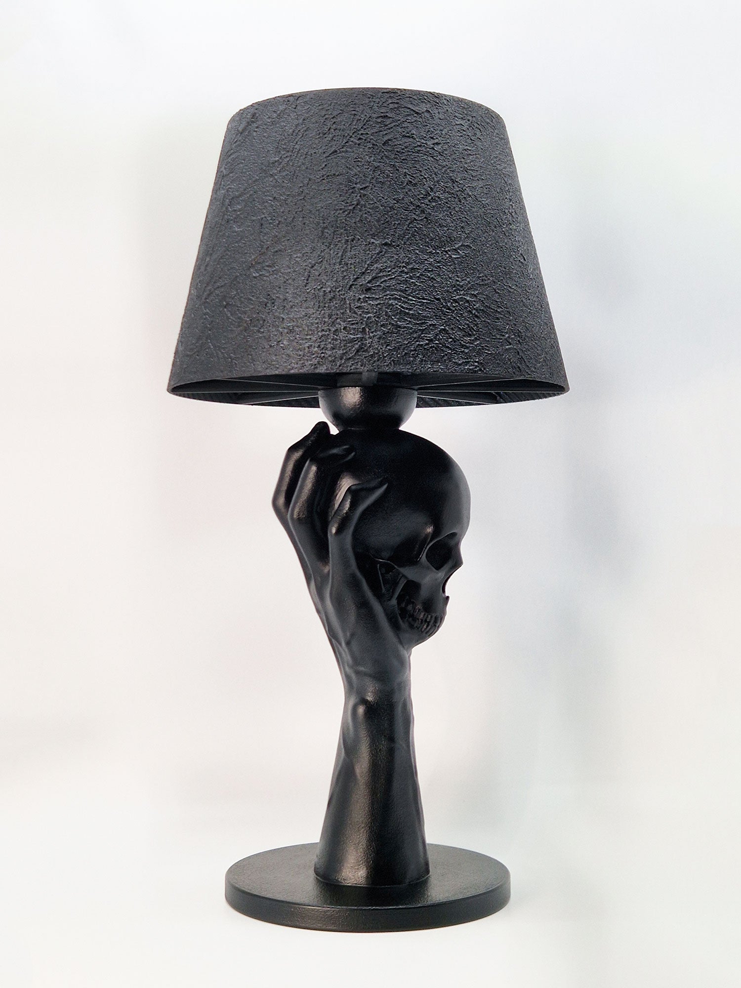 Side profile of the Hamlet-inspired lamp showing the anatomical details of the hand and the skull sculpture.