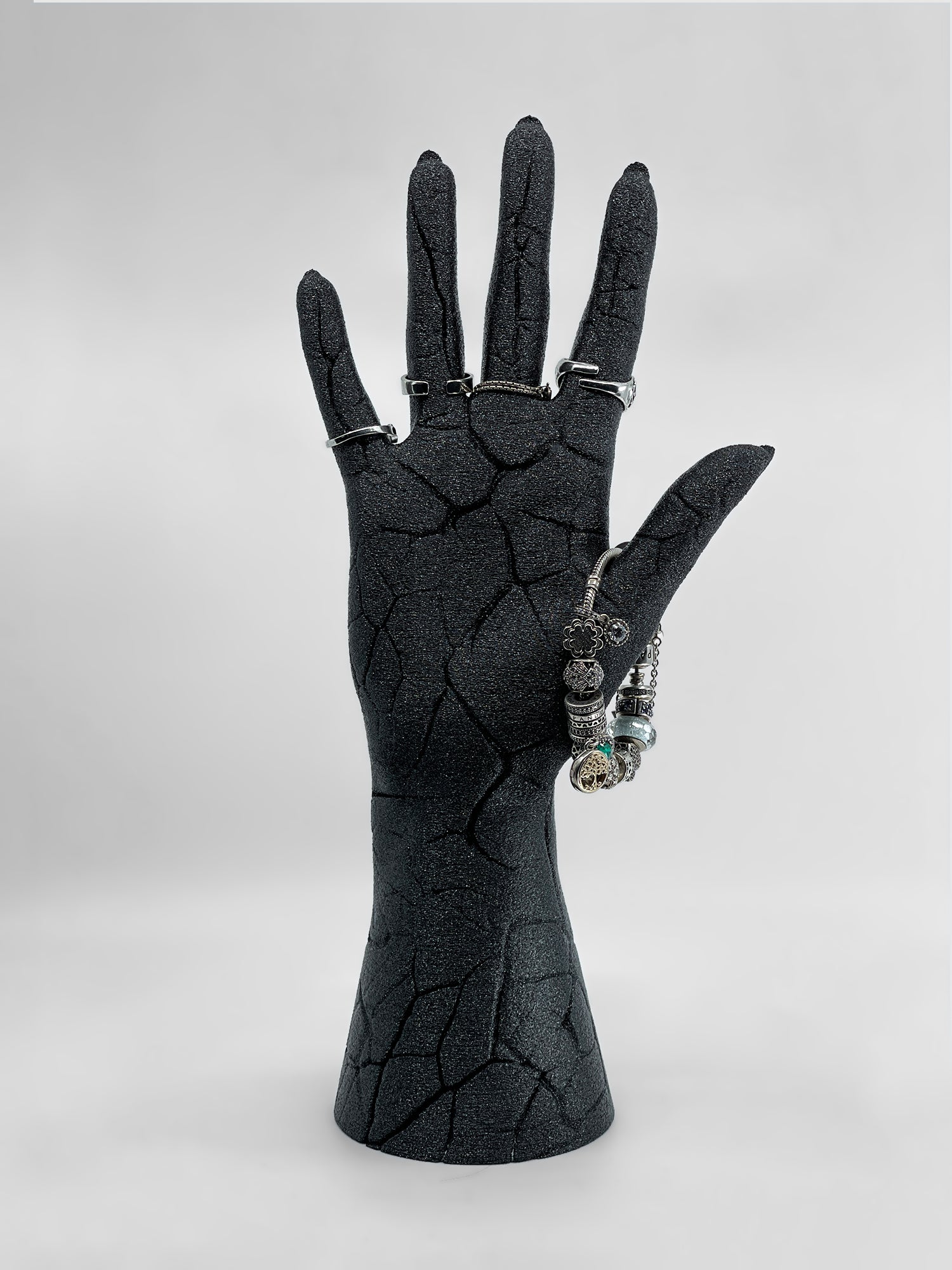 Full view of the anatomical broken hand sculpture used to display gothic silver rings and a charm bracelet.