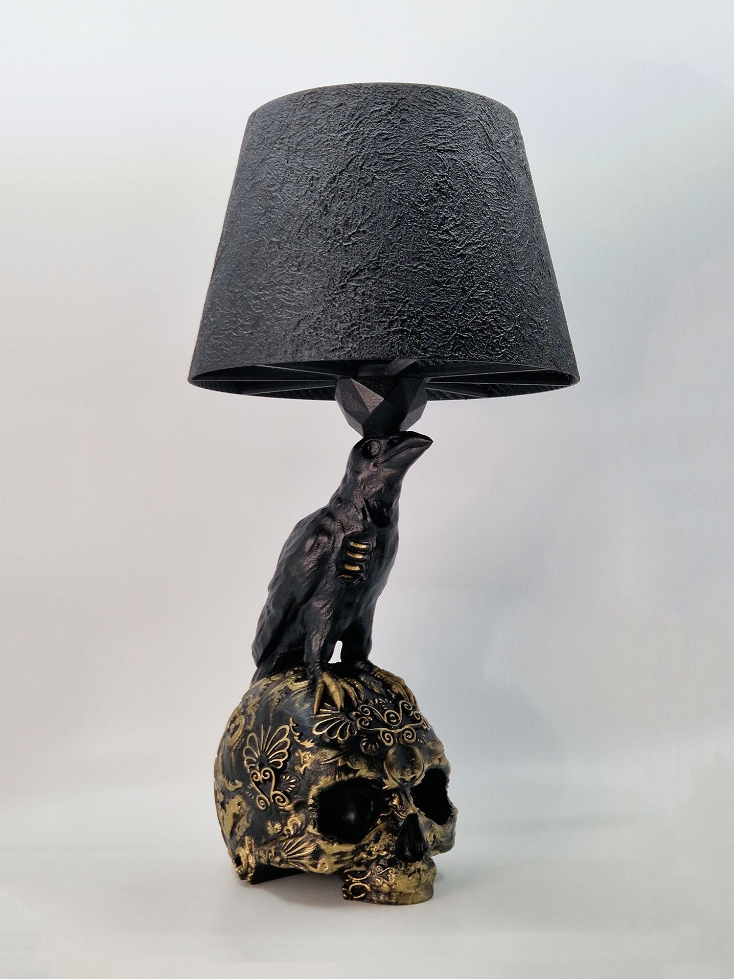 Side view of the Raven Skull lamp showing the intricate gold carvings and textured black lampshade.