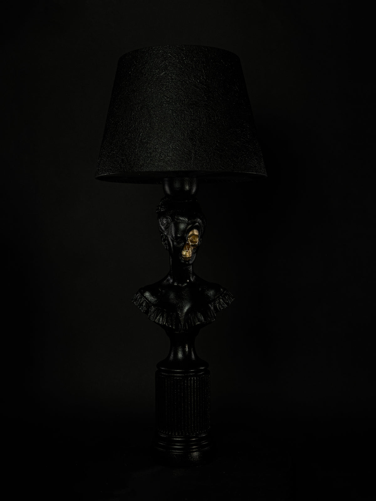 Front view of the Hera classical bust lamp with gold skull and textured black shade