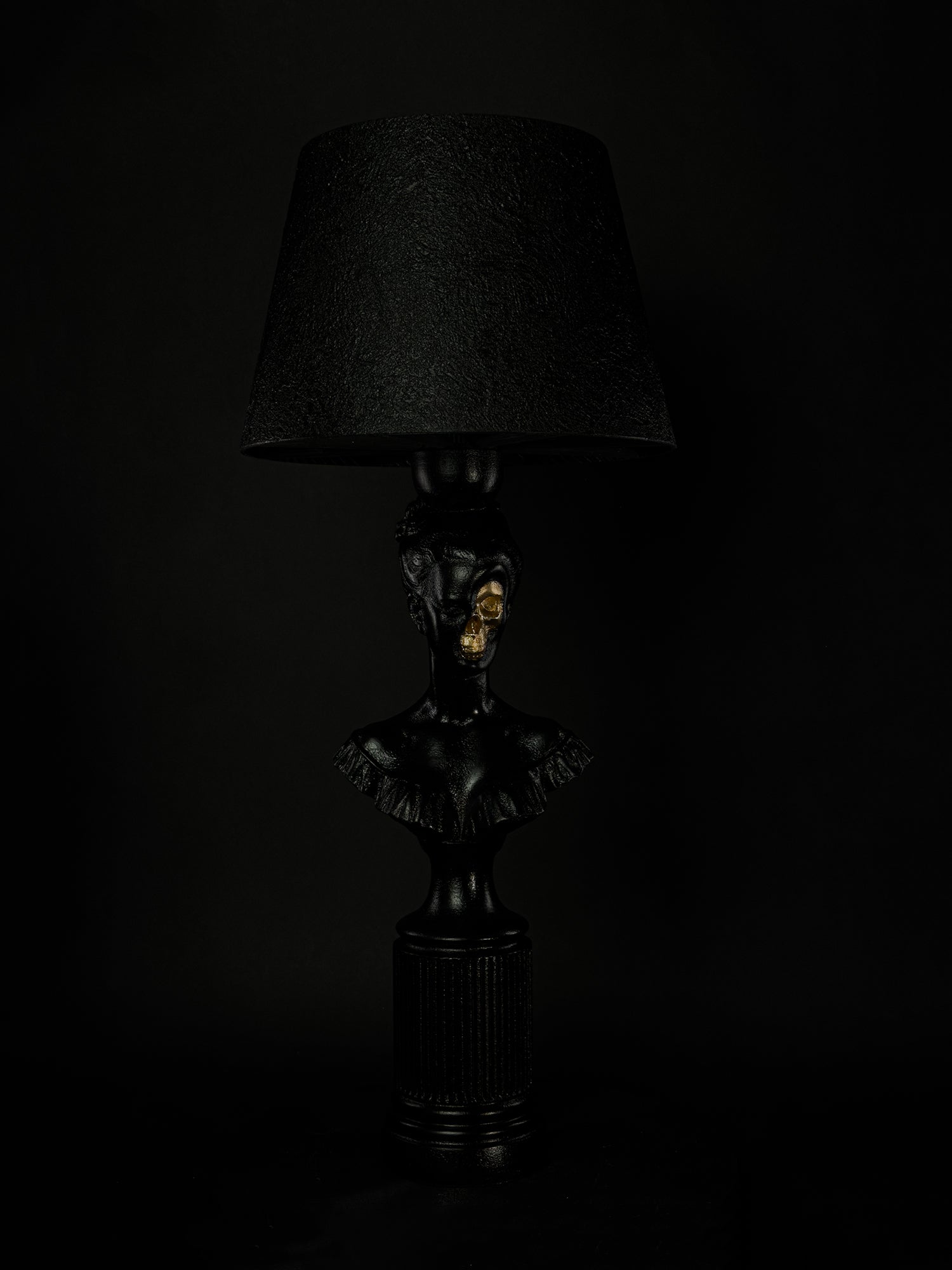 Front view of the Hera classical bust lamp with gold skull and textured black shade