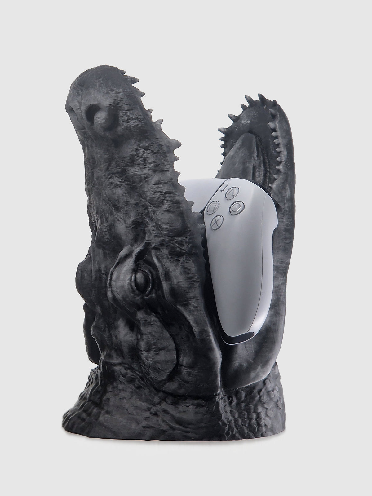 Profile view of the large crocodile jaw controller stand in matte black, holding a white gaming controller.