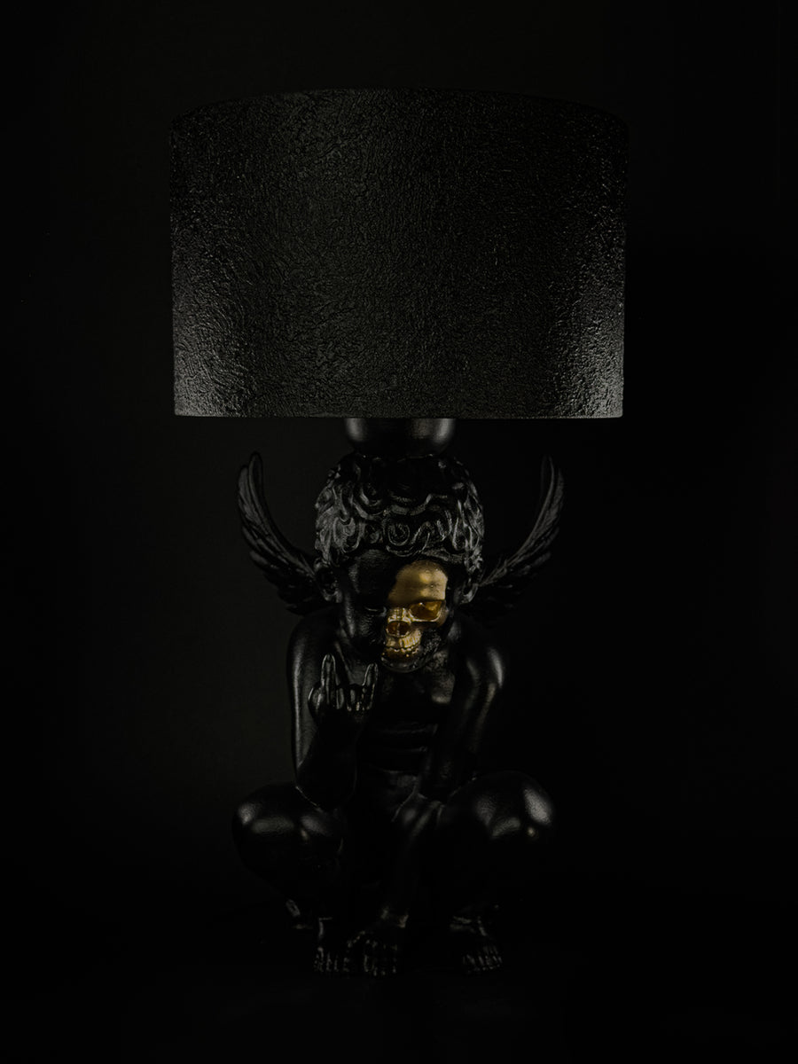 Rebel Angel black cherub lamp with a gold half-skull face, raised wings and a textured black shade.