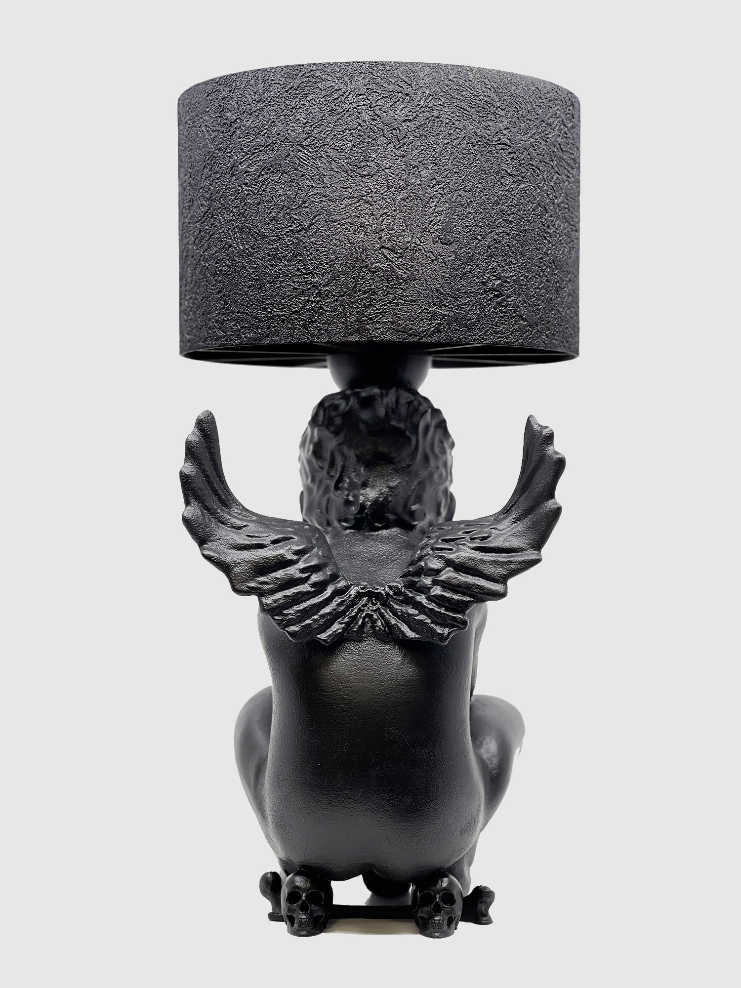 Back view of the Rebel Angel lamp highlighting the intricately carved angel wings and three-skull base.