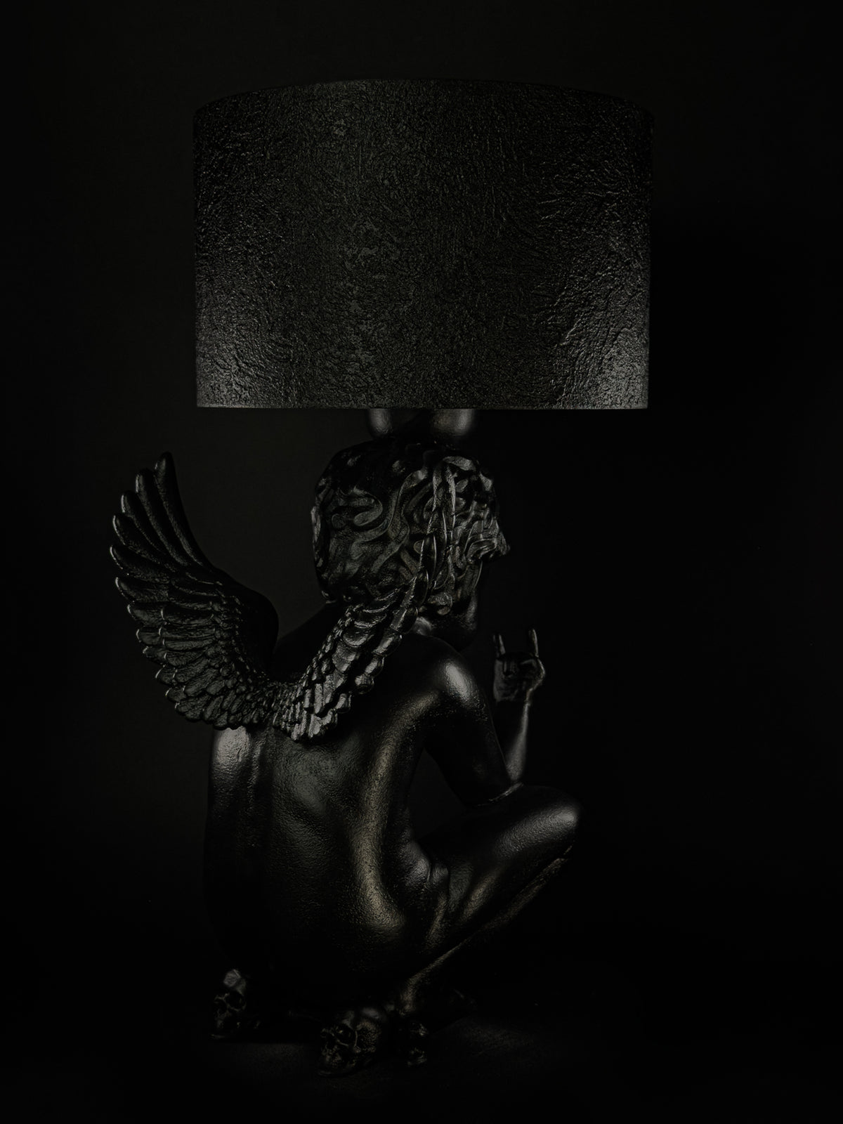 Rear three-quarter view of Rebel Angel lamp showing sculpted wings, hair and a raised hand.