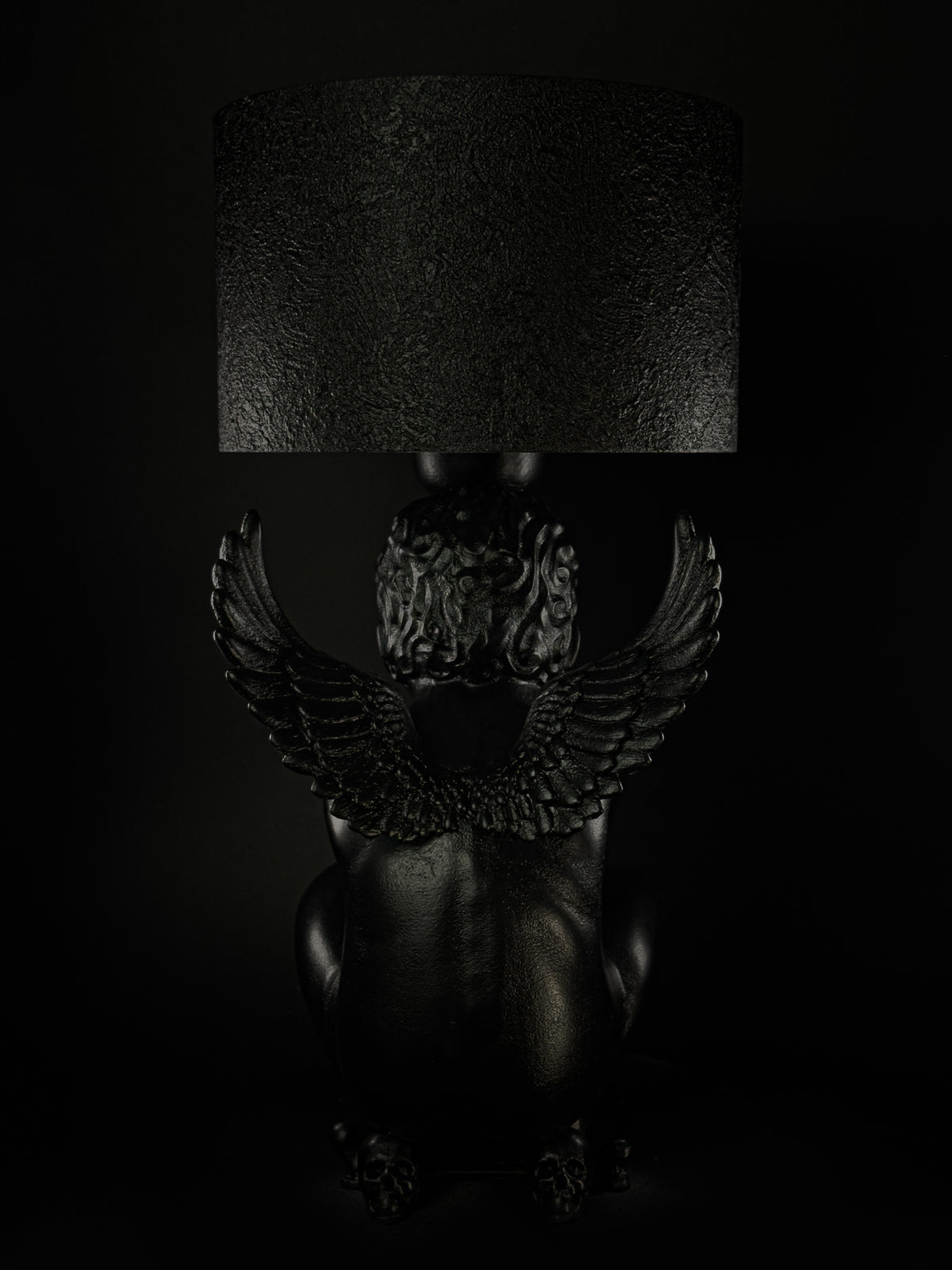 Back view of Rebel Angel black cherub lamp, showing the paired wings beneath its textured shade.