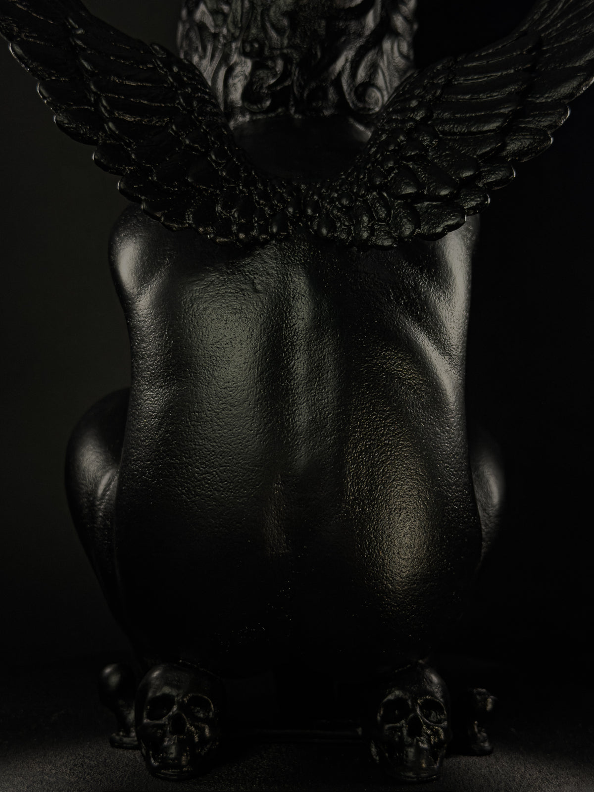 Rear close-up of Rebel Angel lamp showing the cherub's wings, textured back and skulls at the base.