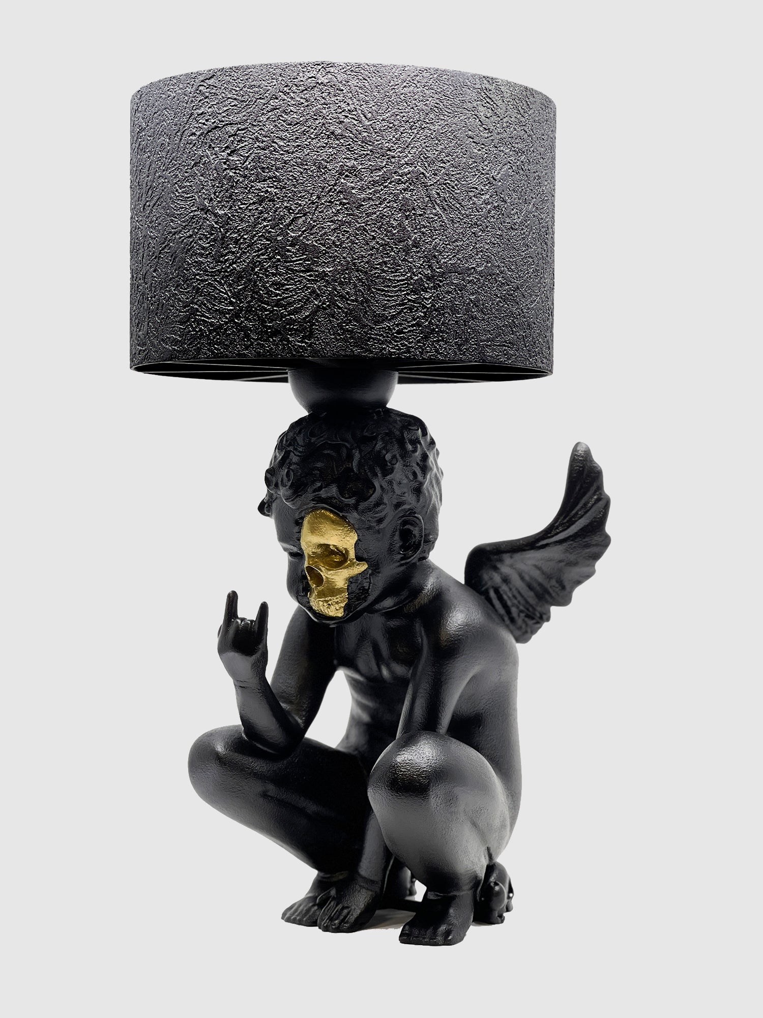 Angled view of the Rebel Angel lamp showcasing the gold-plated half-skull face and rebellious hand pose.