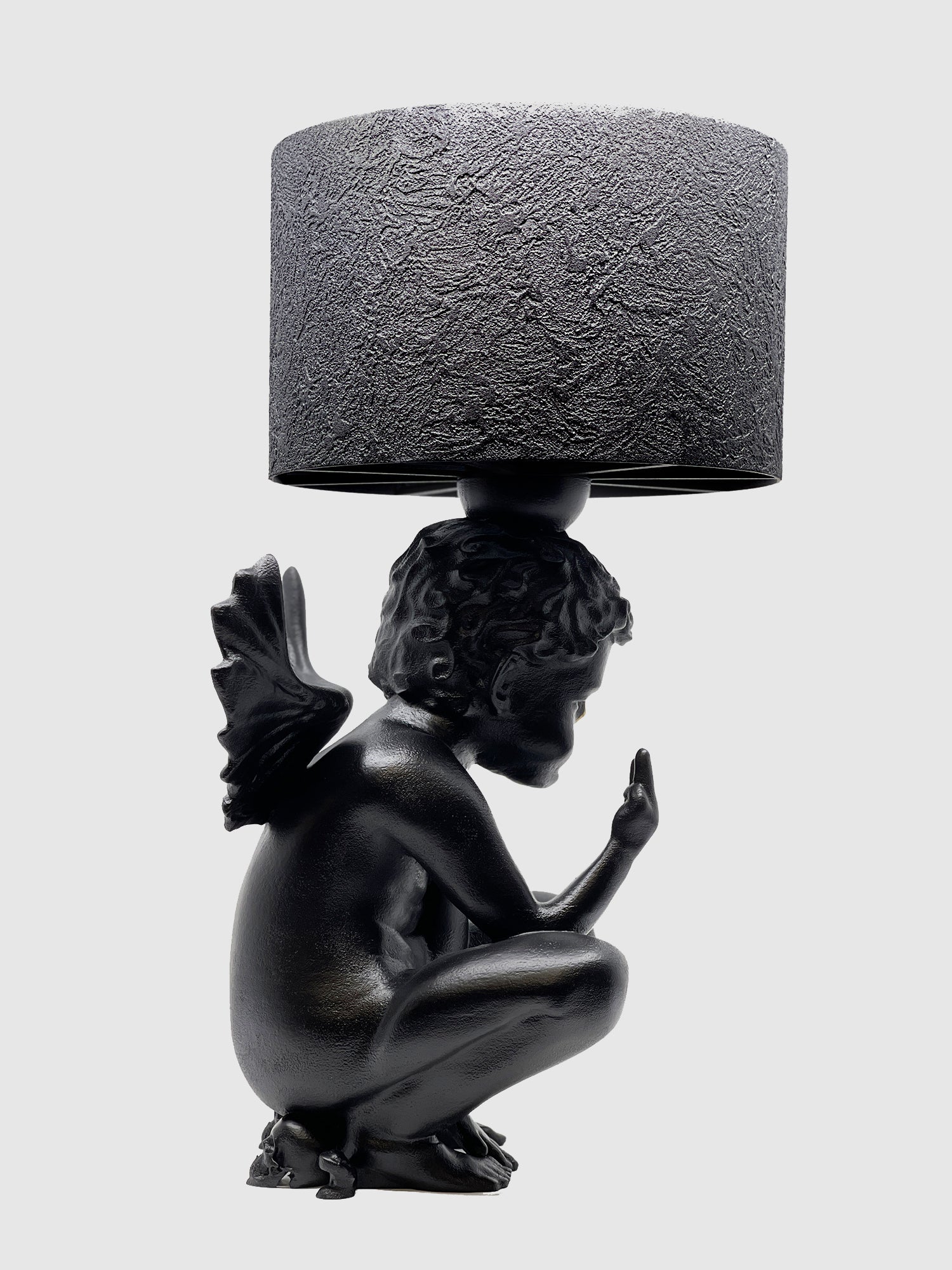 Profile view of the Rebel Angel cherub lamp showing the textured black lampshade and matte black finish.