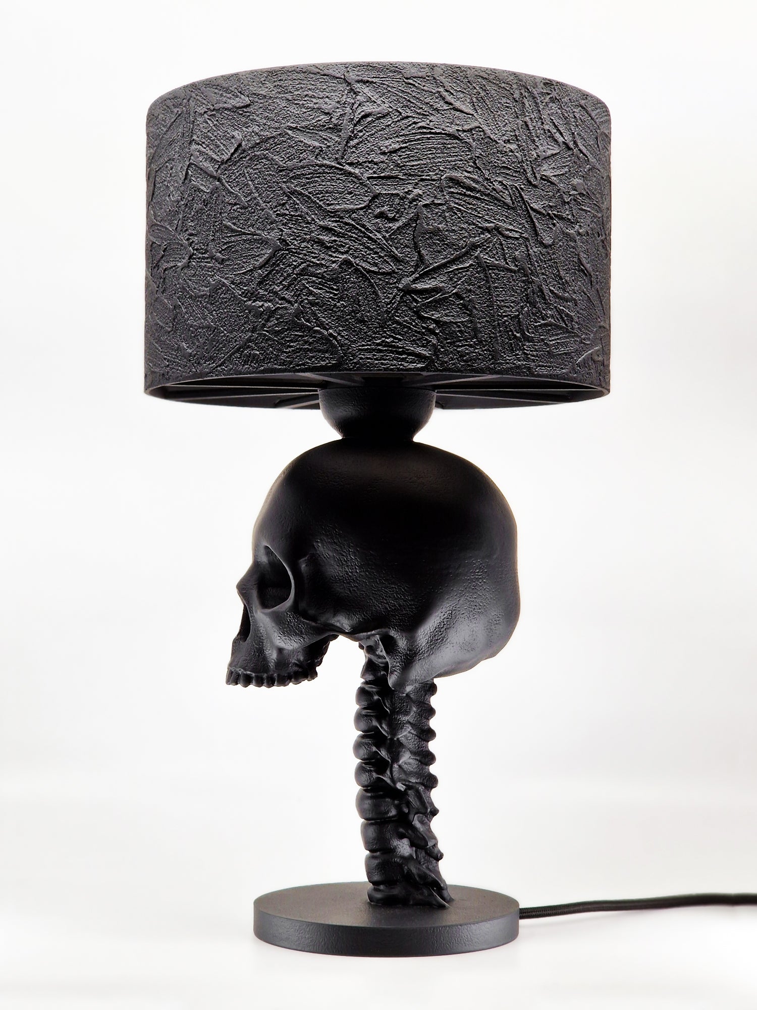 Close-up of skull on Skull Spine Lamp, showcasing eerie details in black plastic.