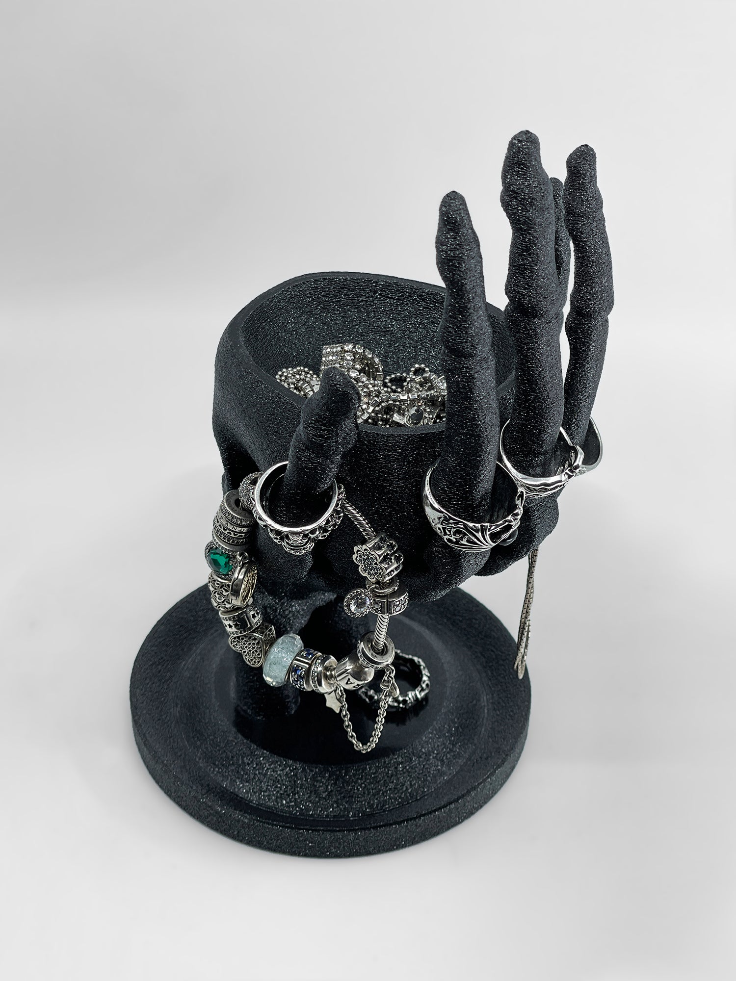 Lifestyle shot of the Skull and Hand organizer being used to display silver gothic rings and bracelets.