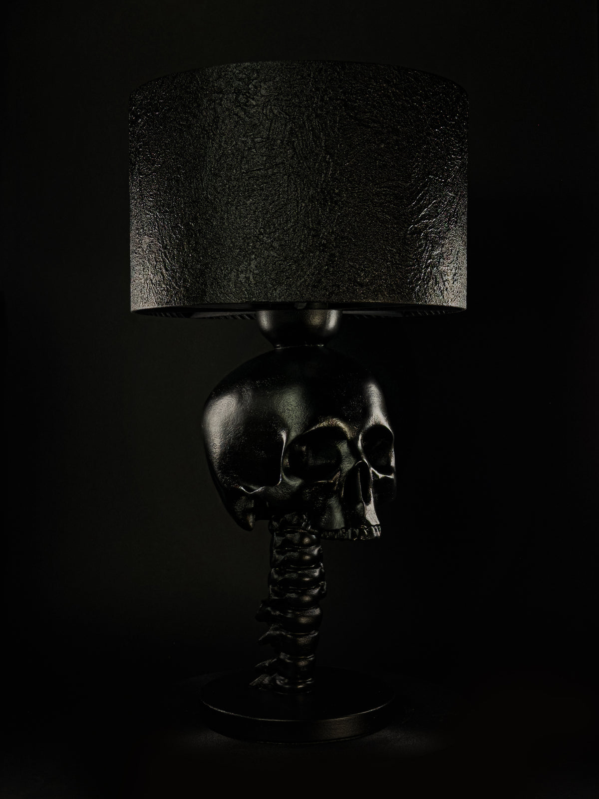 Black Skull Spine sculptural table lamp with textured shade, shown from a three-quarter angle