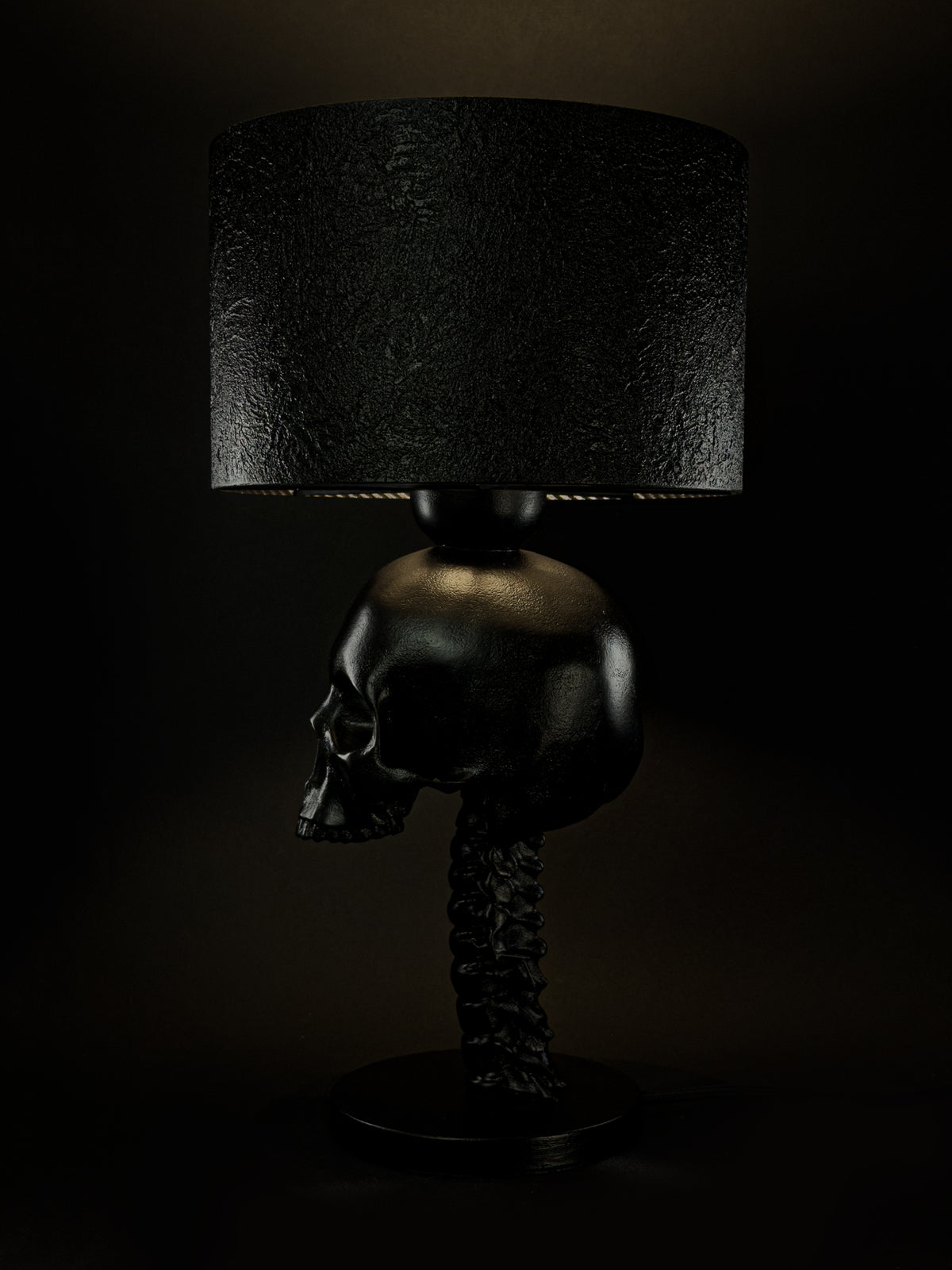 Side profile of the illuminated Skull Spine table lamp with skull and vertebral column