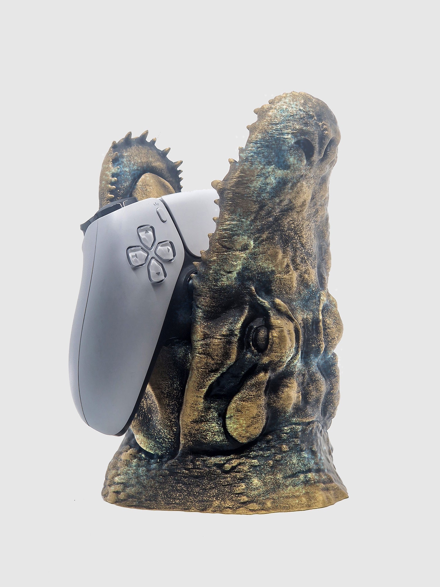 Front view of the small crocodile jaw controller stand in gold patina, shown holding a white PS5 controller.
