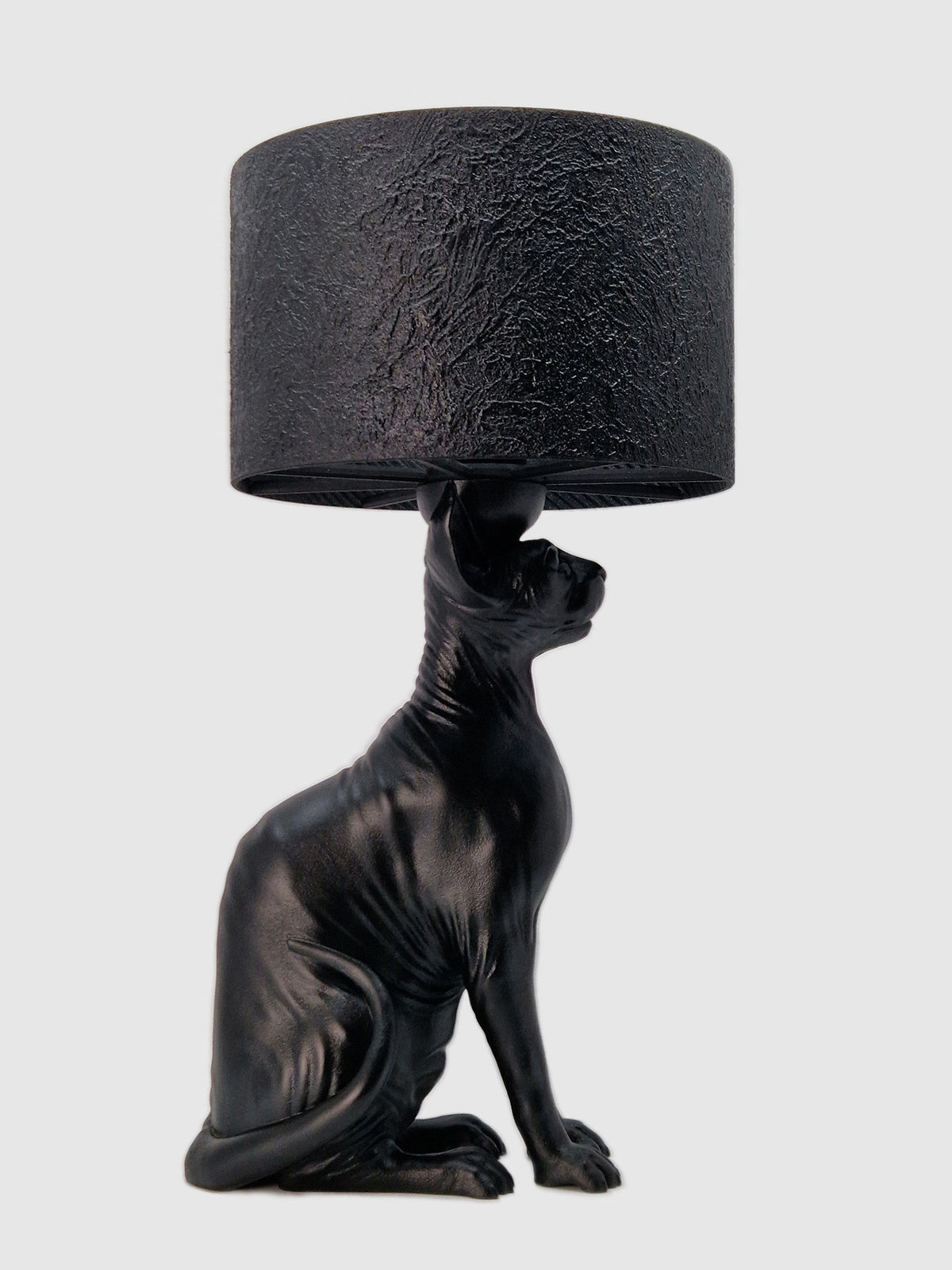 Profile view of a matte black Sphynx cat table lamp with a textured black cylinder lampshade. Designed and manufactured by Horror Romance