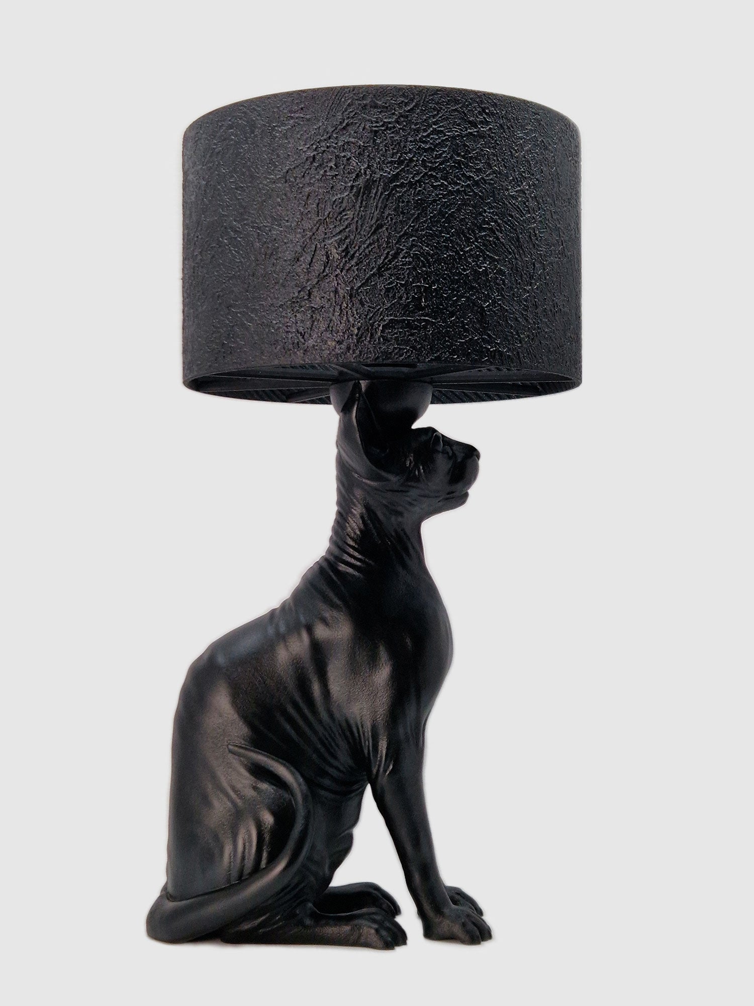 Profile view of a matte black Sphynx cat table lamp with a textured black cylinder lampshade. Designed and manufactured by Horror Romance