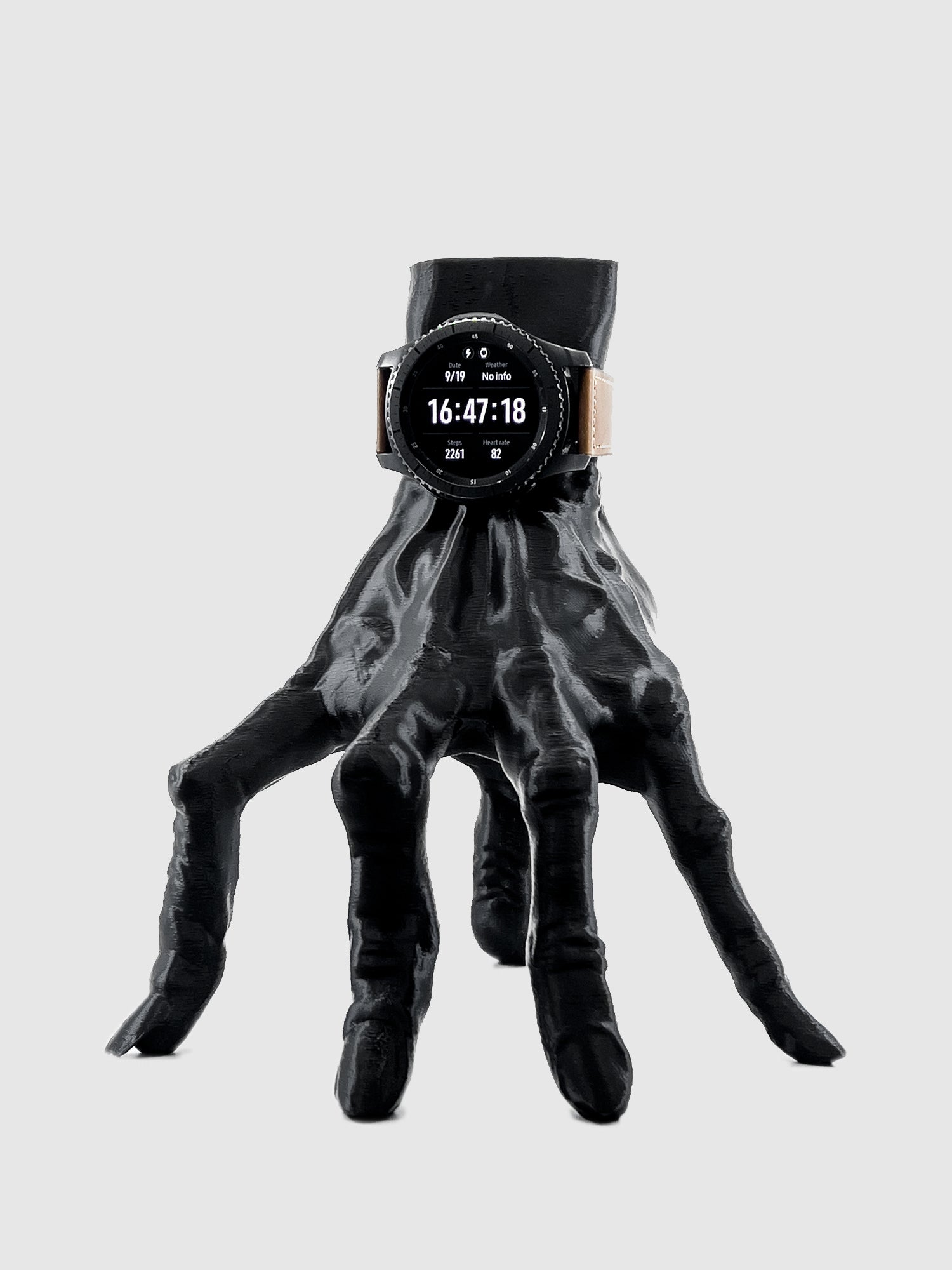 Front view of The Lost Hand smartwatch charging dock in matte black, shown with a watch attached and charging.