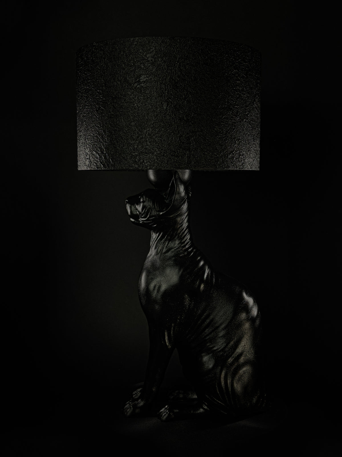Side view of The Watcher black Sphynx cat lamp, showing its seated posture and curled tail.