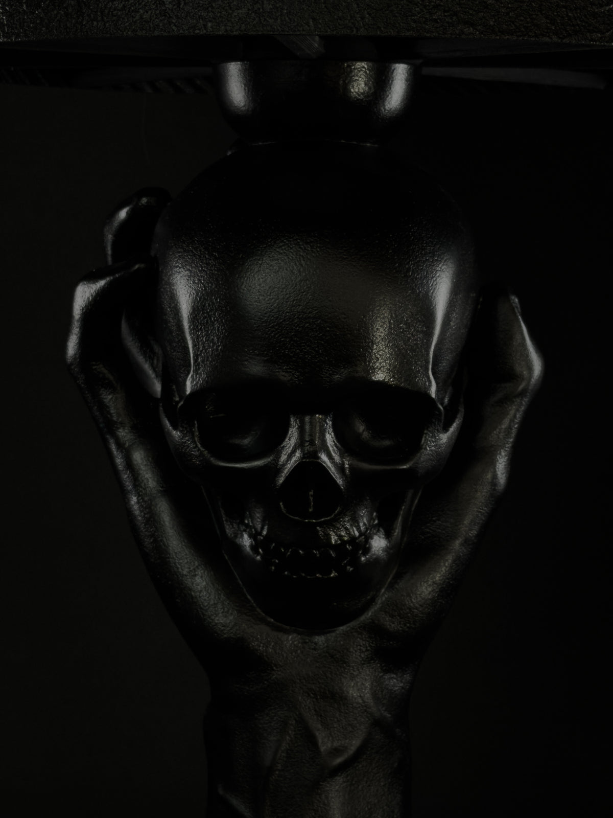 Front close-up of the black skull cradled by a sculpted hand on the To Be or Not To Be lamp.