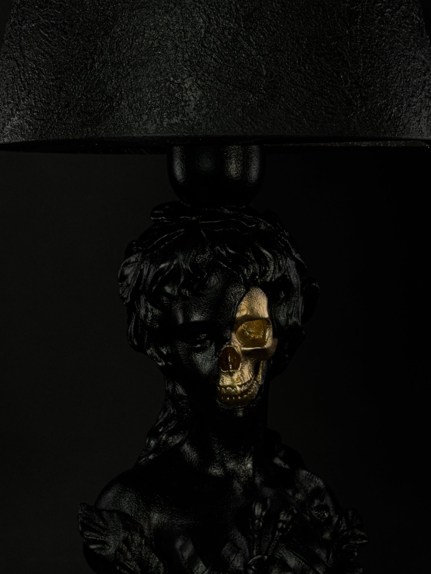 Close-up of the Venus sculptural lamp showing the gold skull beneath the black classical face