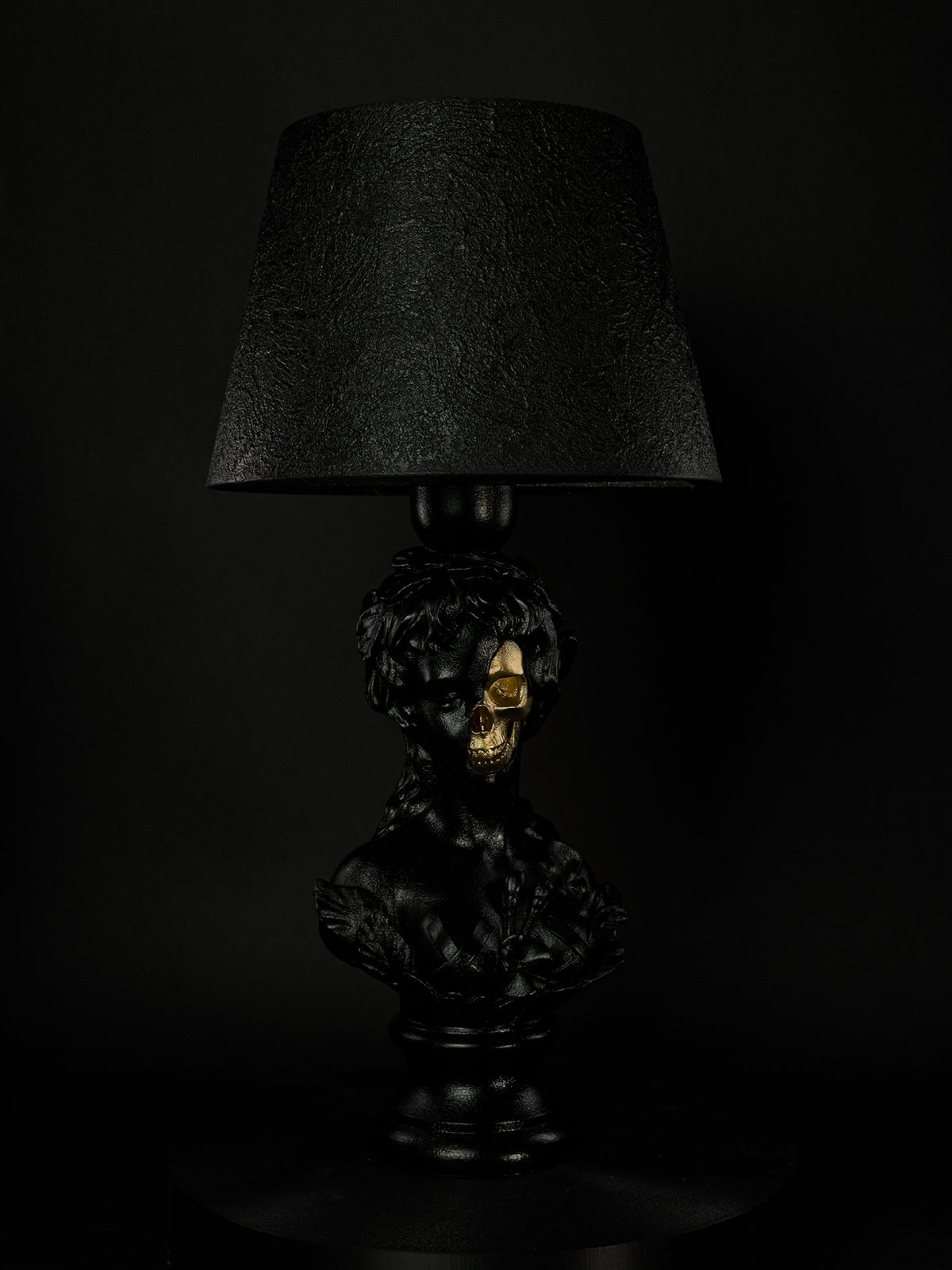 Front view of the black Venus classical bust lamp with exposed metallic-gold skull