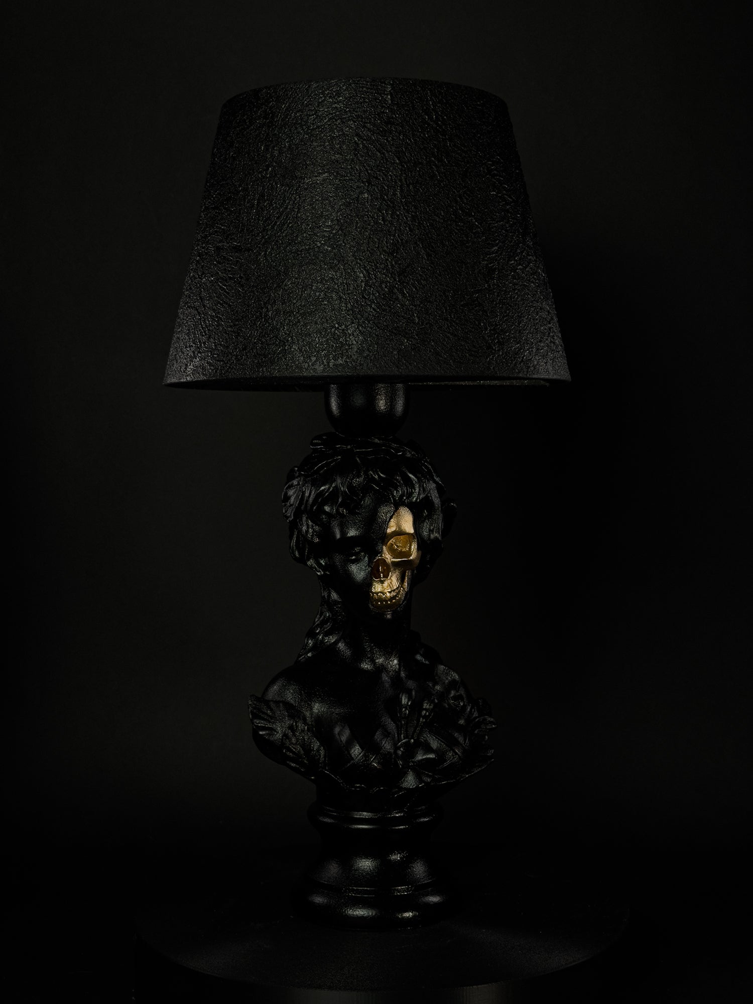 Front view of the black Venus classical bust lamp with exposed metallic-gold skull