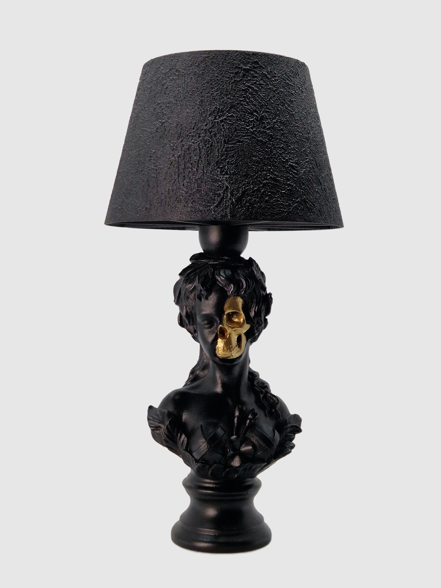 Front view of the Venus Goddess bust lamp in matte black with a gold-plated half-skull face detail, created by Horror Romance.