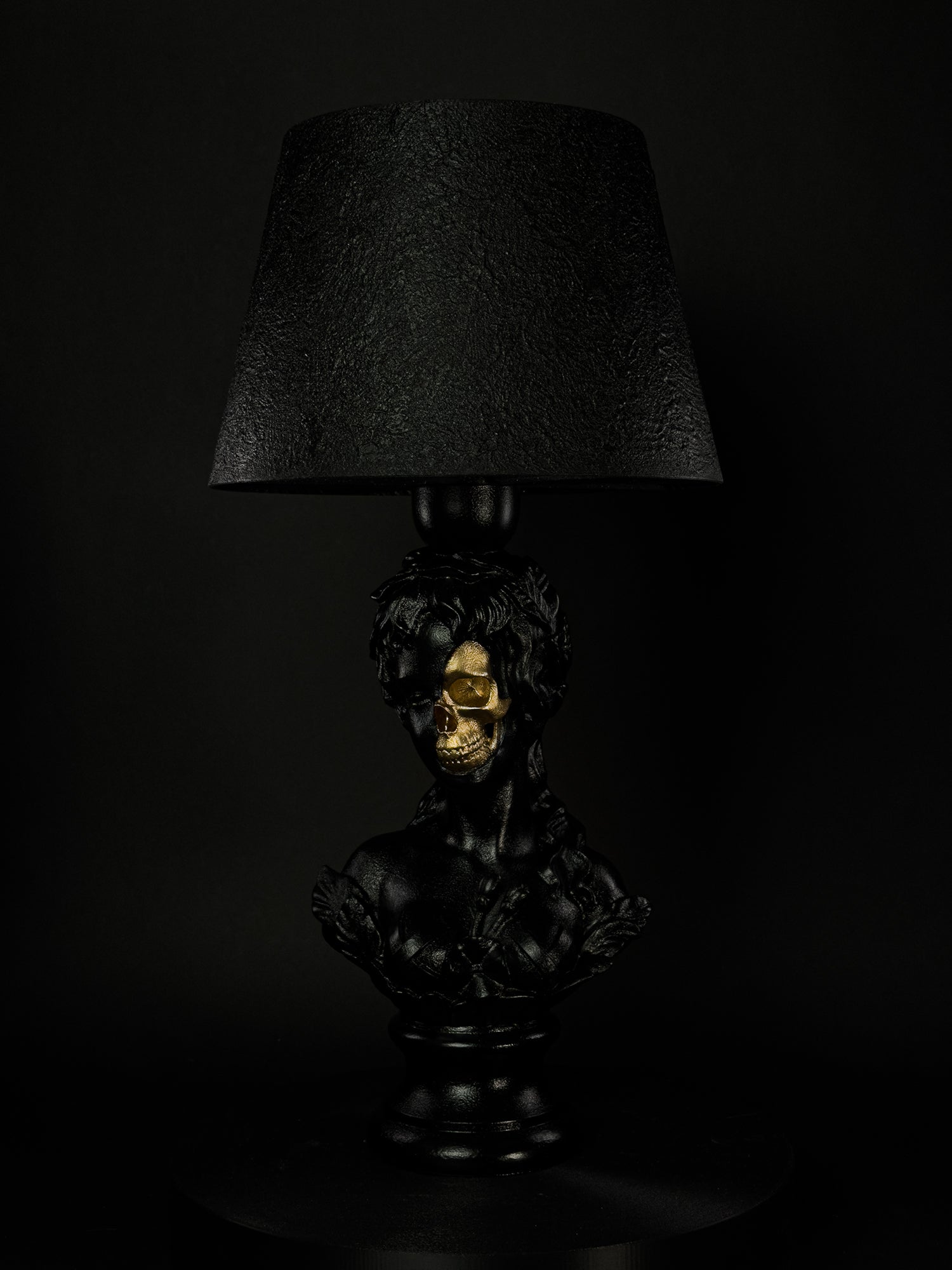 Venus sculptural lamp in satin black with exposed gold skull, shown from a three-quarter side angle