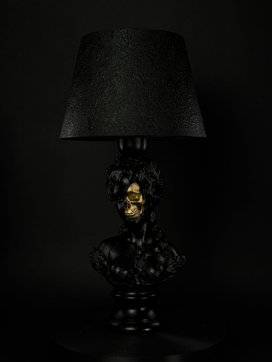 Venus sculptural lamp in satin black with exposed gold skull, shown from a three-quarter side angle