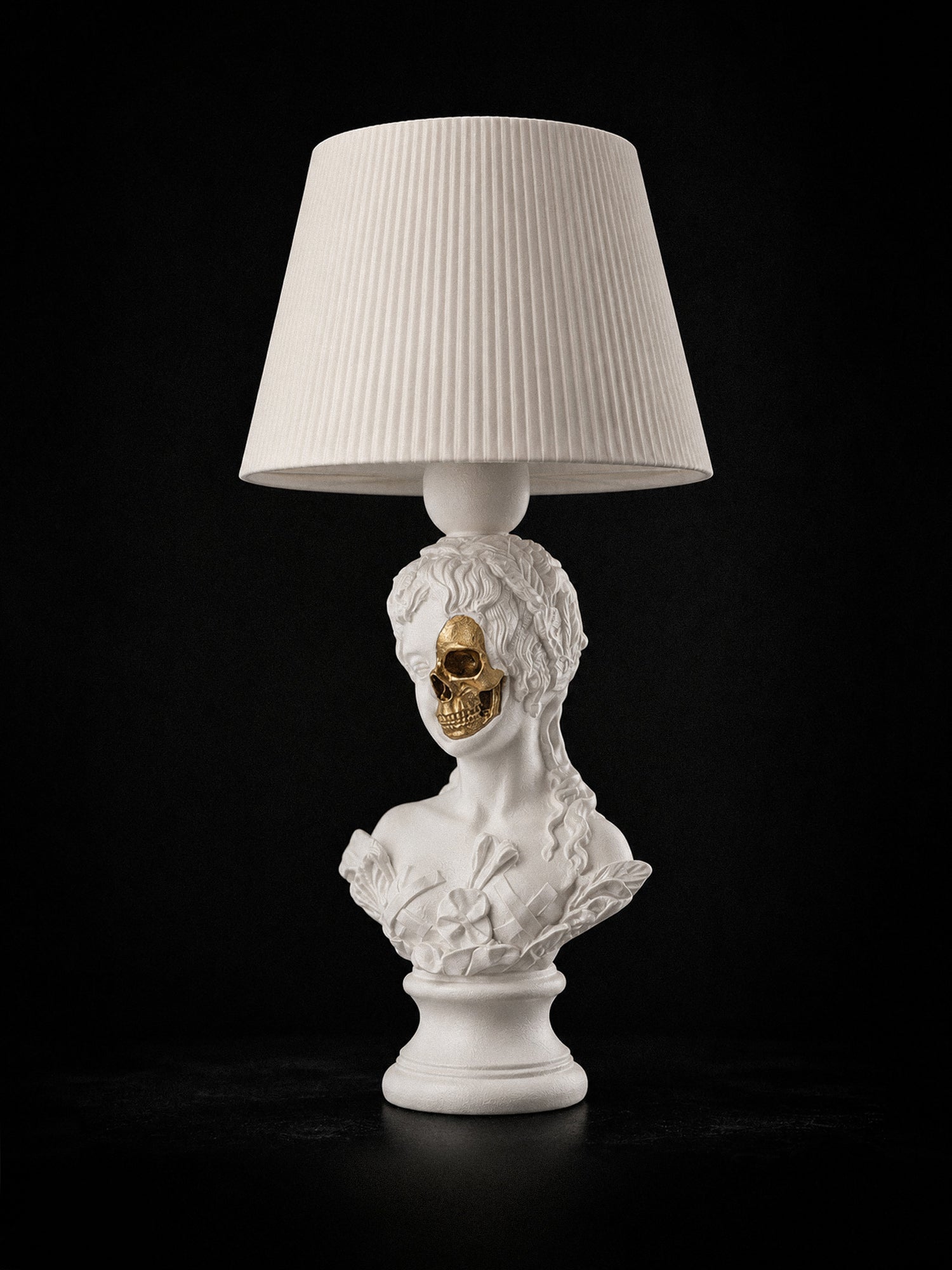 White Venus sculptural lamp with exposed metallic-gold skull and white pleated shade