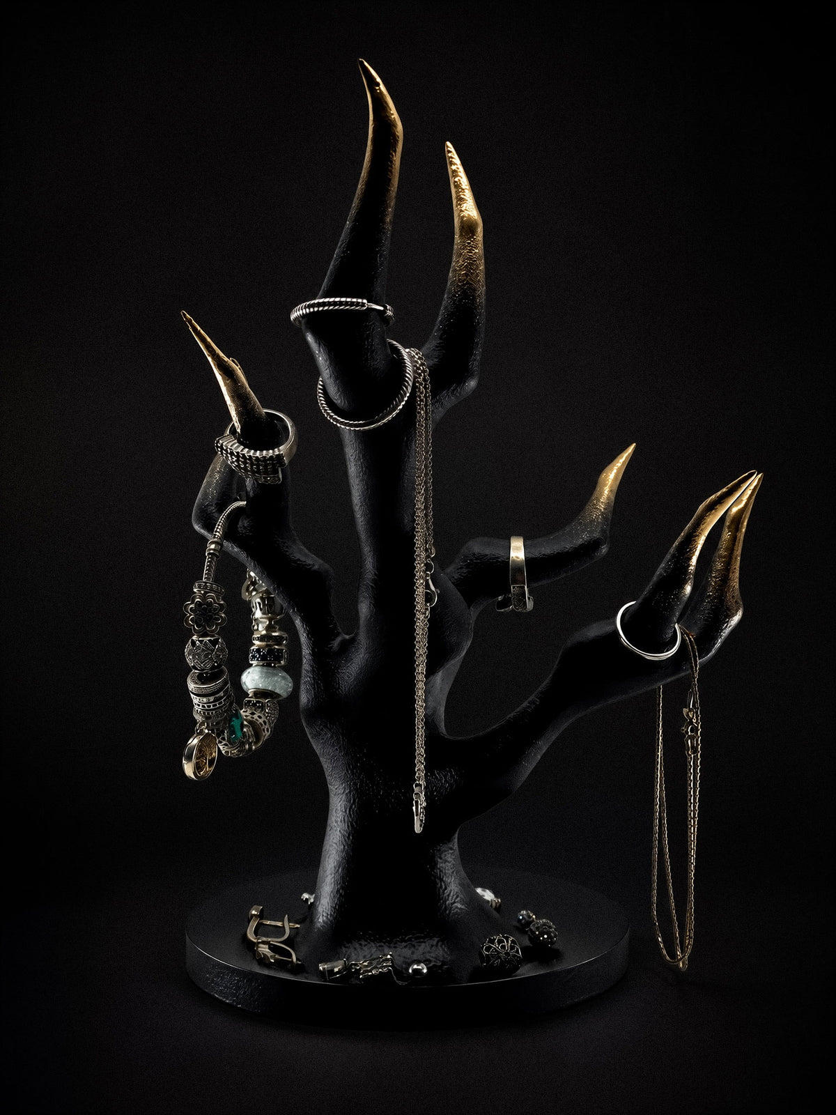 Reverse view of Vestige black and gold skeletal hand stand with rings and hanging necklaces.