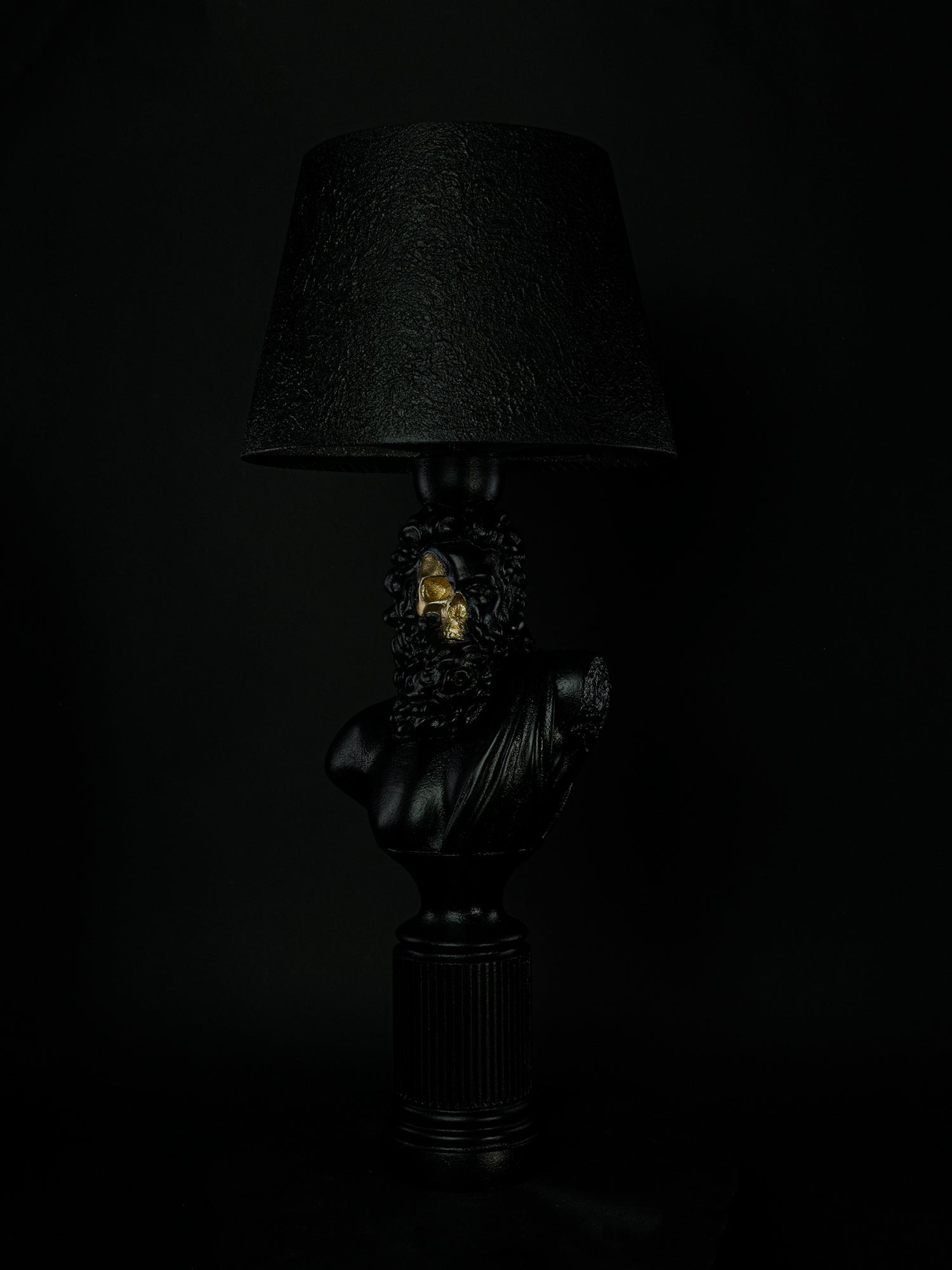 Front view of the Zeus bearded bust lamp with metallic-gold skull and textured black shade
